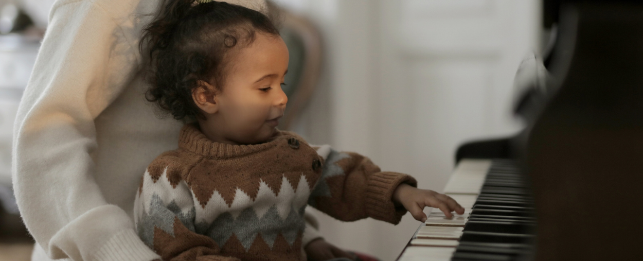 toddler in brown sweater playing piano
