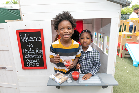 two children in playground house with welcome sign